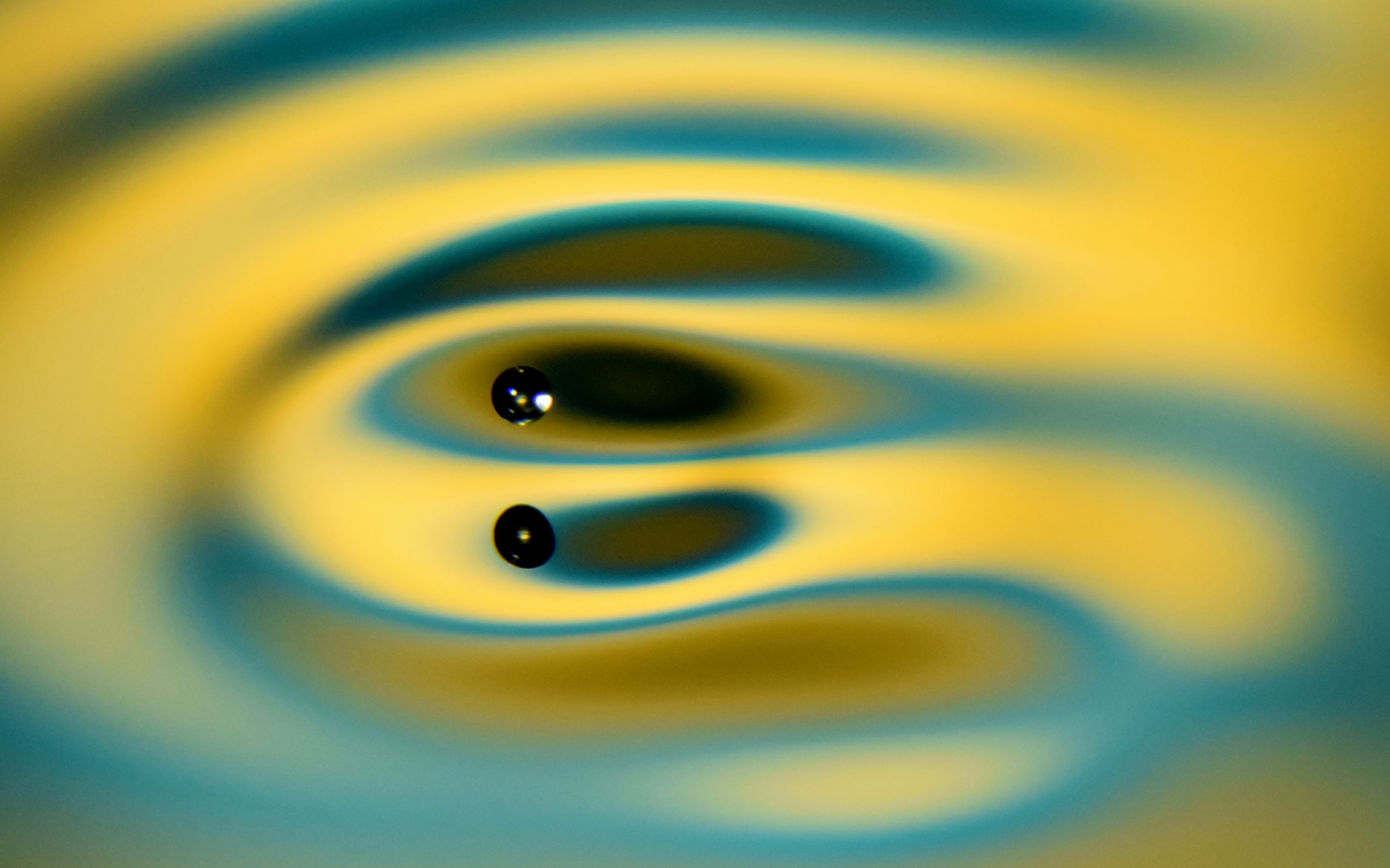 A millimeter-sized oil droplet can bounce on a vertically vibrated liquid bath for an unlimited time. It may couple to the surface wave it emits, leading to horizontal self-propulsion as an object called a walker. Its motion is captured optically with a Nikon camera while an LED light is illuminated through a diffuser (array of blue and yellow colour sheets).
