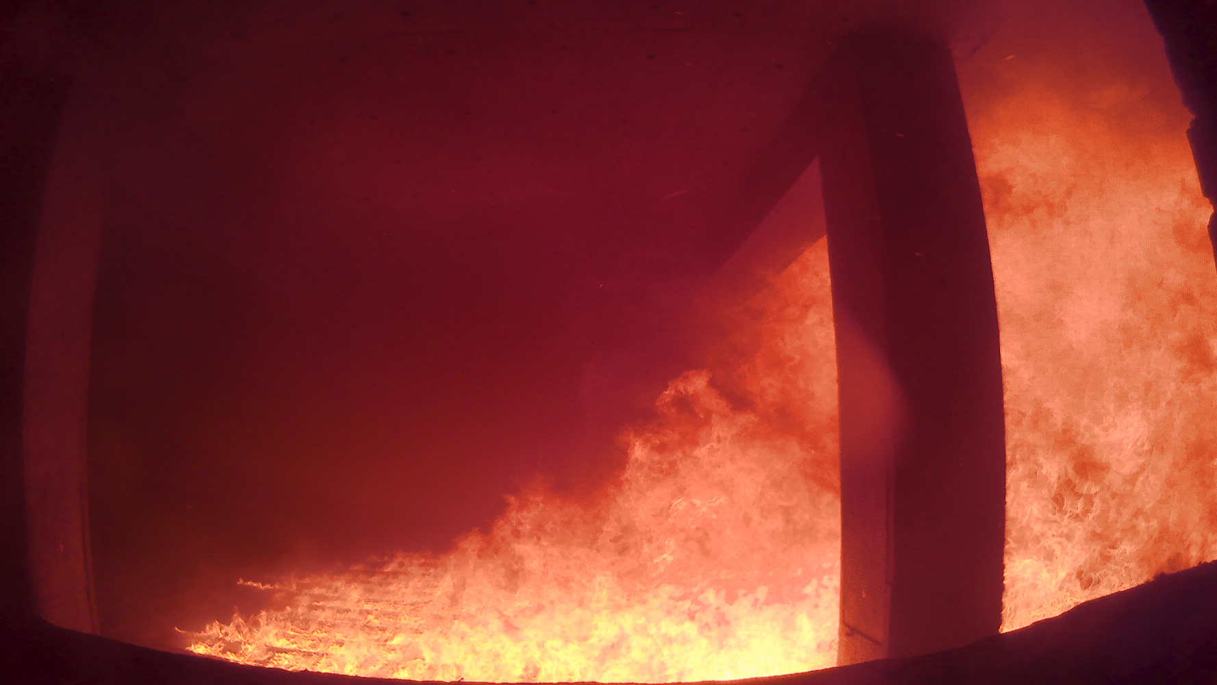 Photo taken from inside the world's largest indoor fire experiment, performed by Imperial Hazelab and collaborators in May 2019. The fire front spreads along unburned wood in the left of the photo (the leading end) and fully develops into large blaze on the right (the trailing end).
